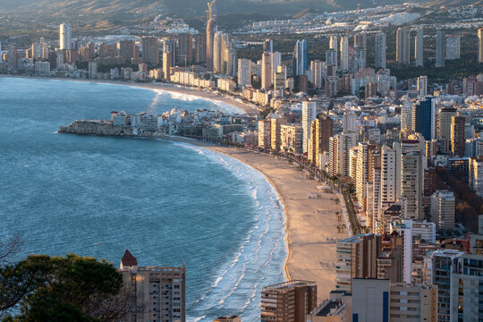 Aerial daylight beach coastline sea bay and waterfront skyline with buildings in benidorm spain showing curved shore panorama from above