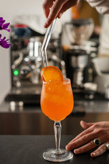 Barman preparing Aperol Spritz under warm bar lights. Captures reflections, bubbles, and glowing orange color of the classic cocktail