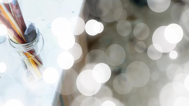 Soft white bokeh overlay drifting from right, obscuring brushes and revealing dried paint palette