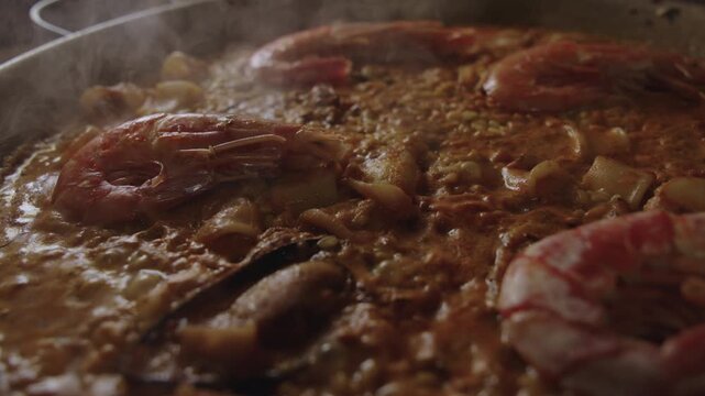 Close up shot of Valencian seafood paella simmering in slow motion with steam bubbles and gentle camera movement