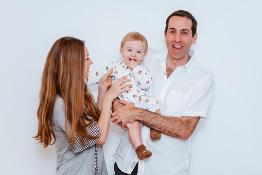 a woman and a man holding up a baby boy in white background