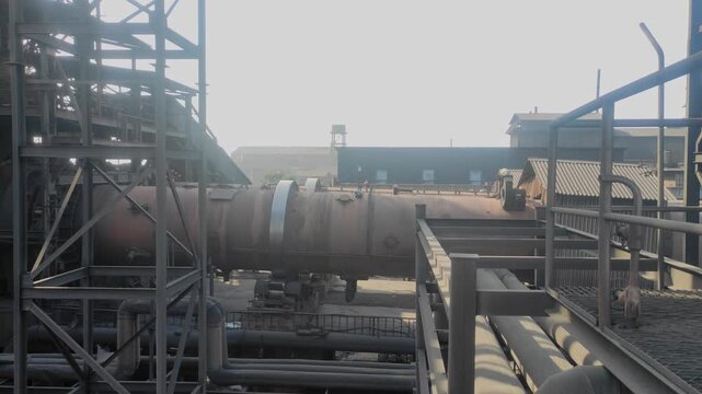 Static view of a sponge iron plant showing a large rotary kiln used for direct reduction, with industrial structures, pipes, and steel frameworks at the facility.