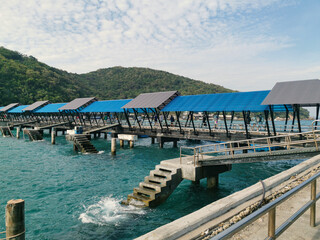 Triangular blue roof of the marine pier on the island, concrete base, ferry on the island on a sunny summer day, pedestrian bridge