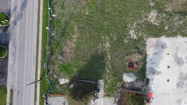 Aerial top down view flying over an urban industrial park with commercial buildings, warehouses, parking lots, and an empty grassy lot. In ajax ontario canada