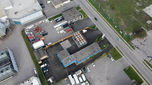 High angle drone view circling an industrial commercial district with warehouses, parking lots, and various vehicles including trucks and boats. In ajax ontario canada