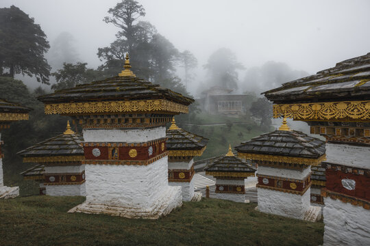 View of the ethereal 108 memorial chortens, gleaming white against the moody mist-shrouded hills, a serene testament to peace, Dochula Chorten, Thimphu, Bhutan.