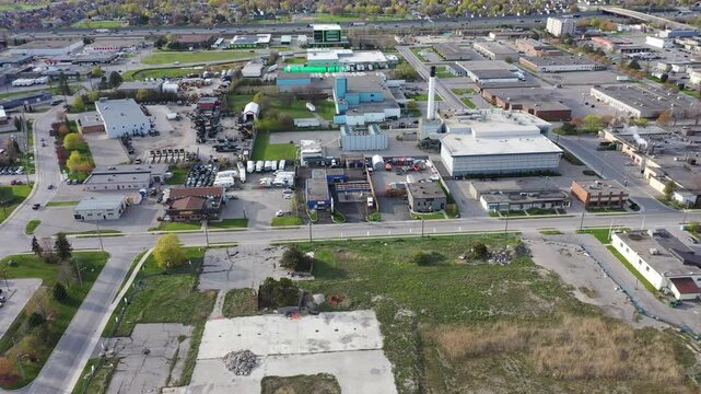 Aerial view flying over a commercial and industrial district with warehouses, factories, and commercial buildings under a clear sky. In ajax ontario canada