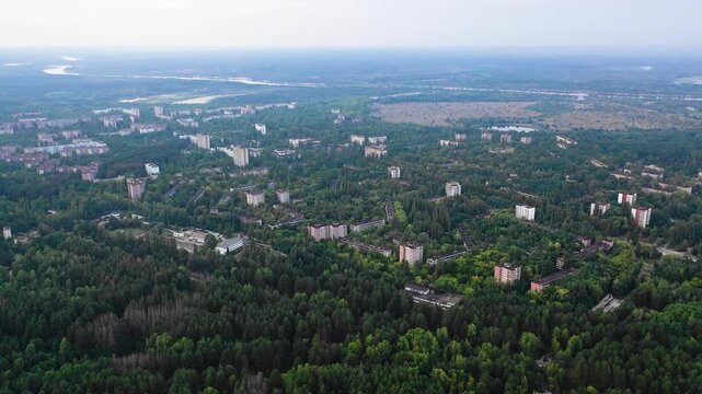 Aerial view of Pripyat abandoned city overtaken by forest and river, evoking eerie isolation.