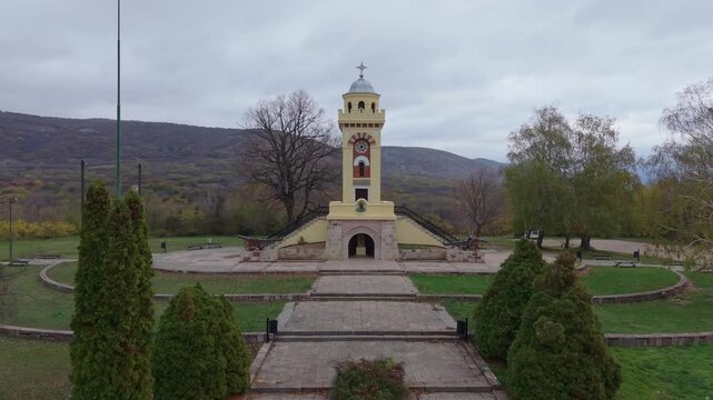 A cinematic drone approach to the Cegar Battle Monument in Nis, gradually revealing the clock on its roof and historic cannons at the base, highlighting its military heritage and cultural significance