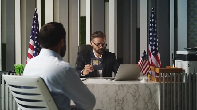 U.S. embassy officer checking U.K. passport and handing document to male visitor
