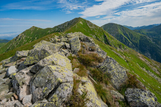 View of jagged rocks lead up to verdant mountain peaks under a vast blue sky, creating a stunning contrast of textures and colors, Magury, Zilinsky kraj, Slovakia.