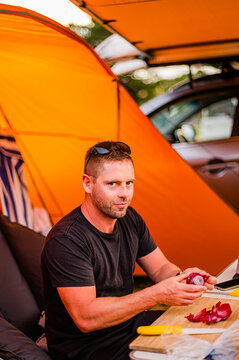a man cooking in a camping ground next to a tent