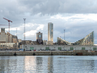 1 august 2025, Aarhus, Denmark. Modern buildings, residential buildings in Aarhus. Modern architecture in docklands. Construction of apartments, building cranes standing. Water in foreground.