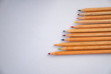 Fototapeta premium Minimal flat lay composition of colorful wooden pencils on a clean white background with copy space, representing creativity, education, and art concept.