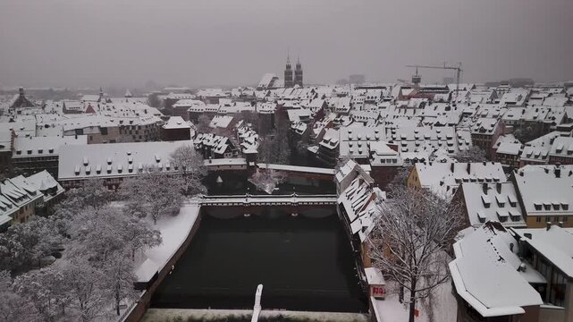 Aerial view on the historic old town of Nuremberg in Germany covered in snow during winter. The Pegnitz river in the foreground with Lorenzkirche in the back.