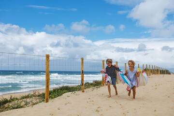 Children have a fun racing to sandy beach with towels in hand