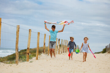 Children walking to ocean beach with toys and towel at vacations