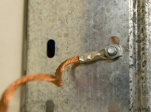Copper multi-strand grounding wire screwed with a nut to a galvanized cable tray