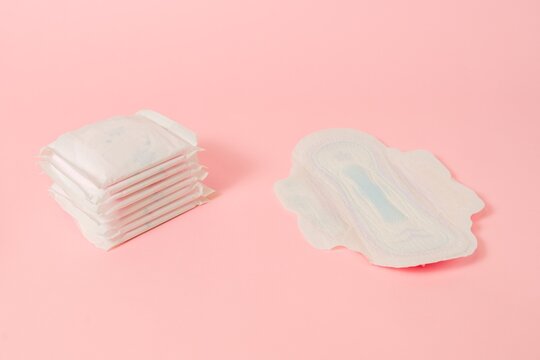 Sanitary napkins packed on pink background. Menstruation cycle, feminine hygiene and protection. Flat layout