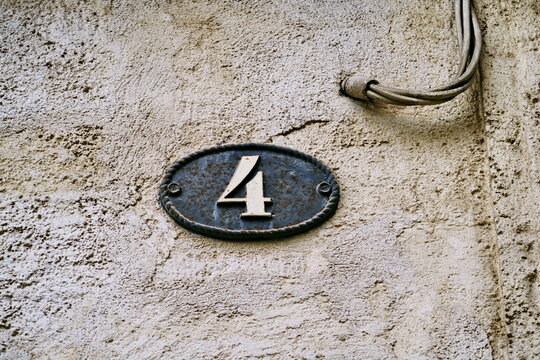 Num&eacute;ro 4. Num&eacute;ro de rue dans un cartouche ovale en fer. Chiffre blanc.