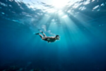Blur image of Freediver man glides underwater in blue ocean with sun rays