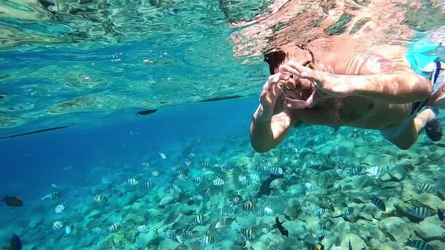 man in sea on face snorkelling mask show by hands heart big love and declaration of love, after two thumbs up super,. trip into water all underwater world to see fish in vacation