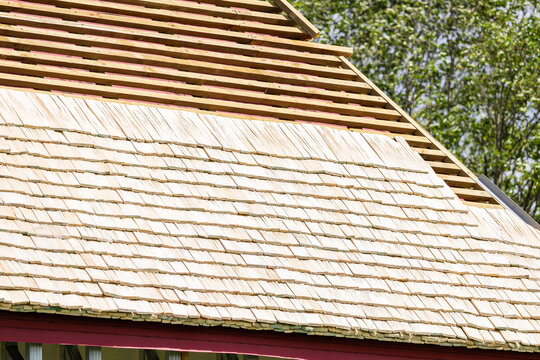 Construction of a wooden shingle (shake, shingle, or shindel) roof. The image shows the process of installing natural larch or aspen wood tiles on the roof battens. Roof truss system.