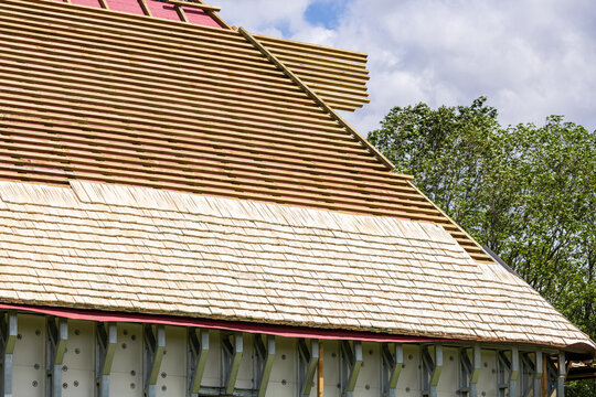 Construction of a wooden shingle (shake, shingle, or shindel) roof. The image shows the process of installing natural larch or aspen wood tiles on the roof battens. Roof truss system.