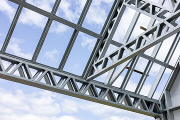 Obraz premium Close-up of a modern galvanized light steel frame LSF construction. Architectural details of roof trusses and wall framing against a blue sky. A sustainable and efficient building material.