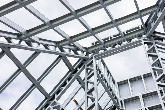 Close-up of a modern galvanized light steel frame LSF construction. Architectural details of roof trusses and wall framing against a blue sky. A sustainable and efficient building material.