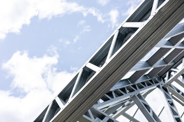 Fototapeta premium Close-up of a modern galvanized light steel frame LSF construction. Architectural details of roof trusses and wall framing against a blue sky. A sustainable and efficient building material.