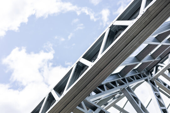 Close-up of a modern galvanized light steel frame LSF construction. Architectural details of roof trusses and wall framing against a blue sky. A sustainable and efficient building material.