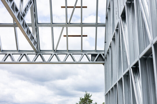 Close-up of a modern galvanized light steel frame LSF construction. Architectural details of roof trusses and wall framing against a blue sky. A sustainable and efficient building material.