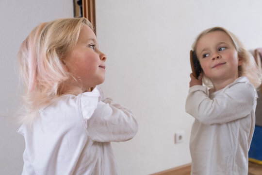 Morning routine of a preschooler. little girl taking care of her hair.