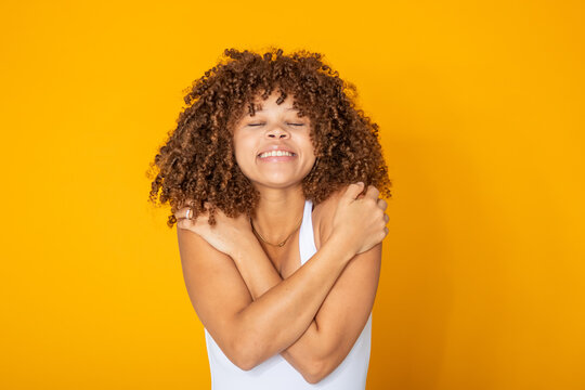 young woman isolated, smiling and hugging herself