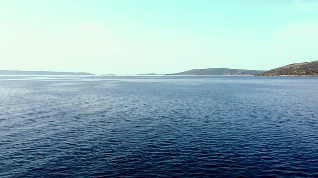 Wide aerial dolly of calm open sea with distant land barely visible on horizon, empty peaceful serene backdrop
