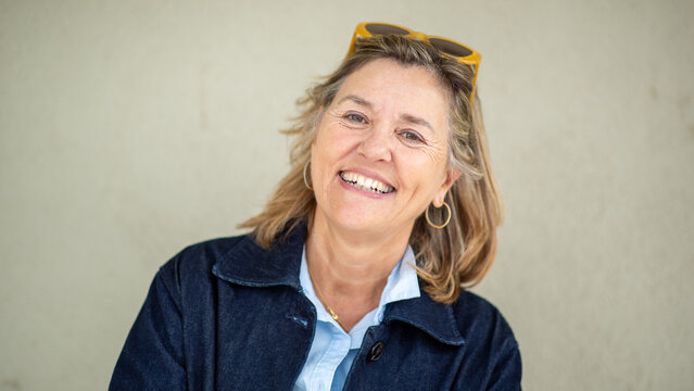 Happy senior woman smiling confidently in front of neutral wall