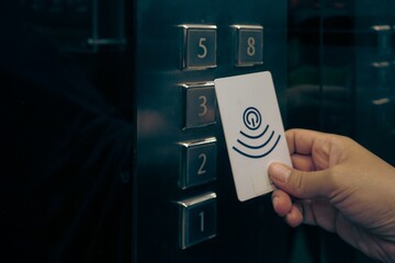 Hand using contactless key card for elevator floor access © Liada