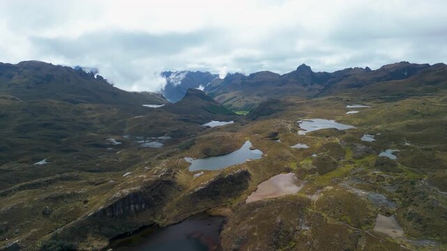 Cinematic drone orbiting shot of the rugged paramo landscape at Cajas National Park featuring glacial lakes and jagged mountain peaks near Cuenca Ecuador