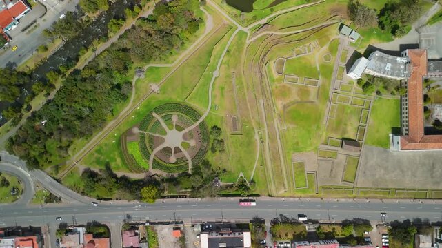 Drone shot looking straight down at ancient stone foundations and geometric garden patterns of Pumapungo archaeological park in urban Cuenca city center