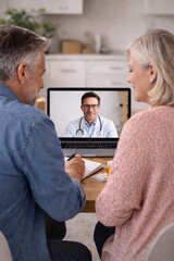 Obraz premium Senior couple video chatting with doctor on laptop in cozy living room at home