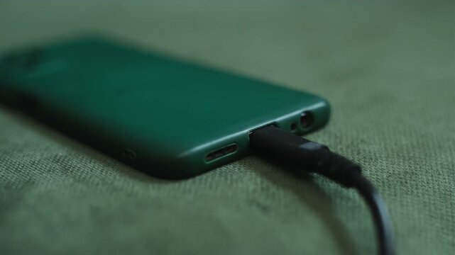 Mobile phone charging. Hands connecting smartphone to charger. Close up.