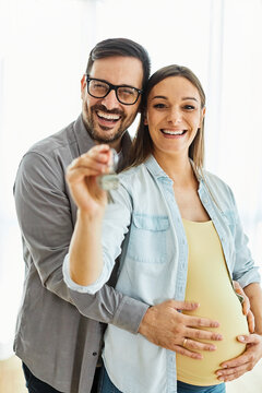 Happy young couple, pregnent woman,  buying a new house and holding the keys