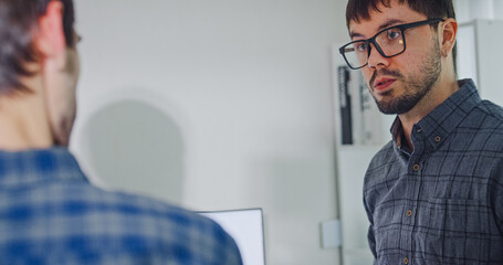 Team adult male engineer collaborate on robotic hand project using AI code solutions machine learning at tech workspace. Artificial intelligence interface, collaboration support prototype development.