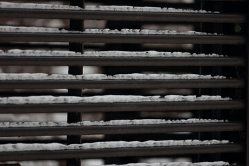 Horizontal Black Metal Bars Of A Fence Covered With Fresh White Snow. Urban Winter Texture Background.