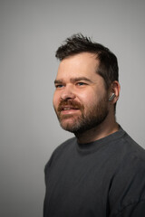 Obraz premium Happy bearded man with wireless earbud in his ear