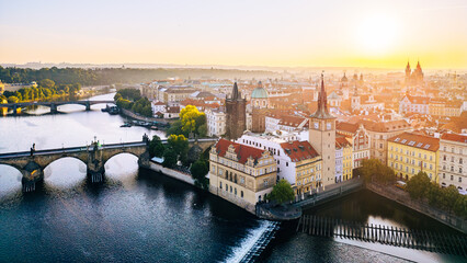 Charles Bridge stands majestically over the Vltava River, connecting the Old Town and Lesser Town. The warm glow of sunrise highlights the intricate details of the Old Town Bridge Tower. © pyty