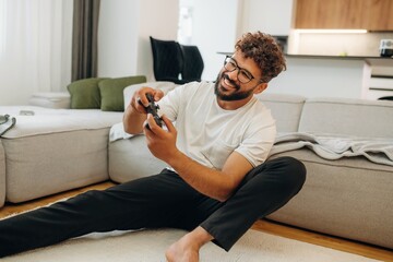 Playing video games by using controller. Man is in the modern domestic room at home