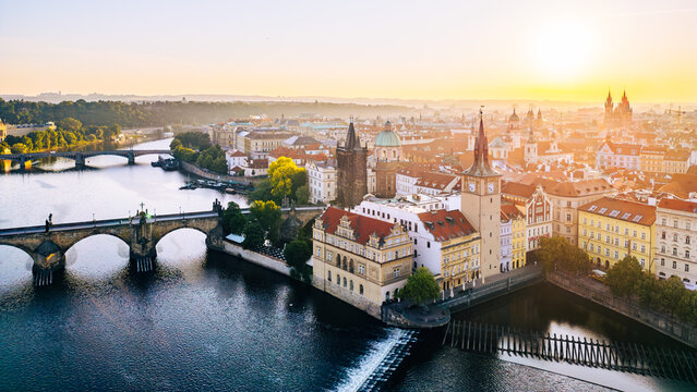 Charles Bridge stands majestically over the Vltava River, connecting the Old Town and Lesser Town. The warm glow of sunrise highlights the intricate details of the Old Town Bridge Tower.