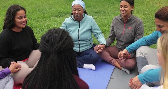 Group of women's circle during a yoga class with females of different age and body types holding hands - Healthy lifestyle, meditation and multiracial people concept
